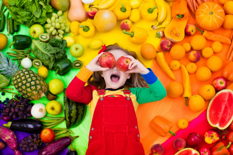 A photo of a child laying on fruits and vegetables.